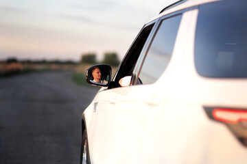 Reflection of an handsome focused European driver in the side mirror of his new white car. Car rental, leasing, loan, adventures, test drive, success, trip car concept.