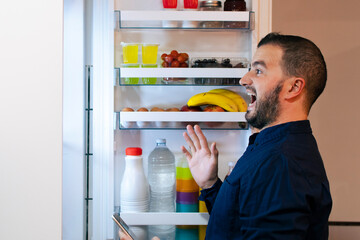 Surprised man looking inside the fridge