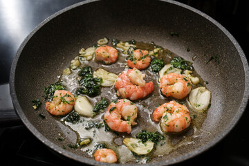 Shrimps or black tiger prawns are sauteed with olive oil, garlic and parsley in a frying pan for a delicious seafood snack, selected focus
