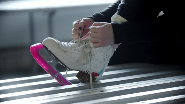 Ice skating - woman ties shoelaces on white skates in the changing room