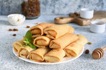 Obraz na płótnie Canvas Thin spring rolls on a light concrete background. Platbands. National, traditional dish of Belarus and Ukraine. Pancakes