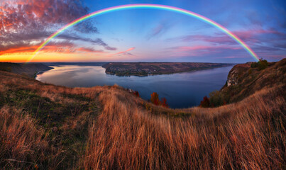 colorful rainbow over river canyon. autumn landscape