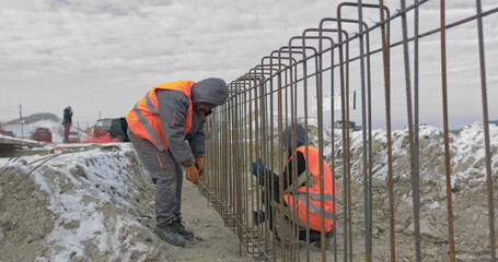 Engineers work with metal constructions while building a house. Builder fixes armature while...