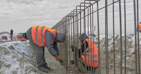 Engineers work with metal constructions while building a house. Builder fixes armature while...