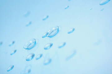 contact lenses, case and tools on a blue background with water drops, all in blur for the background image