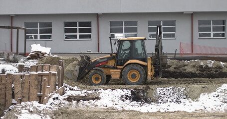 The bulldozer works on a construction site with sand, side view. New Big Tractor, a bulldozer on wheels on a sandy road on a construction site levels the site for the construction of real estate