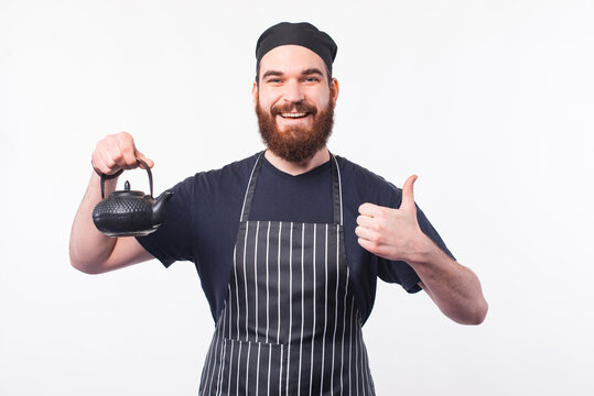 Photo of barista preparing some tea in kettle and showing thumb up.