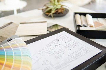 Obraz premium Interior designer's working table, an architectural plan of the house, a color palette, furniture and fabric samples. Drawings and plans for house decoration.