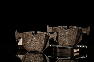 New BRAKE PADS in foreground on black reflective material on black background with negative space.