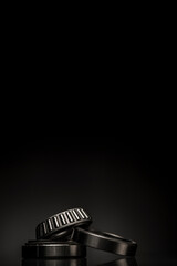 Car bearings, auto parts, steel automotive bearings, placed on black reflective surface, on black background with negative space on top.