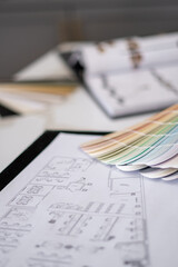 Interior designer's working table, an architectural plan of the house, a color palette, furniture and fabric samples. Drawings and plans for house decoration.