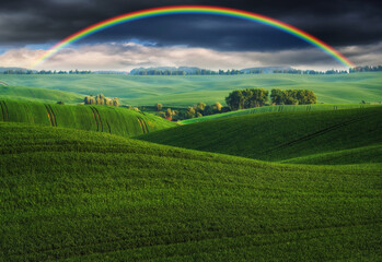 
Scenic view of rainbow over green field. dramatic gray sky over a picturesque hilly field
