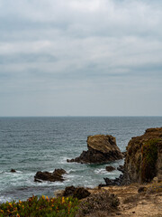 Dark moody cliff, next to ocean and sea, in beach in costa vicentina, alentejo, portugal