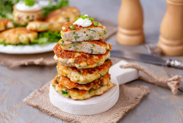 Stack of chicken patties with cheese and spring onion. Wooden background, selective focus.