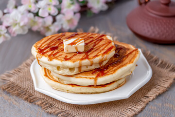 Stack of fluffy Japanese Style souffle pancake cake on white plate. Dark wooden background, selective focus.