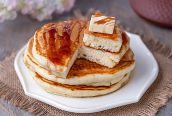 Fluffy Japanese Style souffle pancake sliced  on white plate over wooden surface. Selective focus
