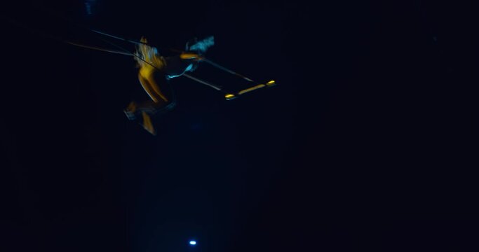 Circus acrobat is performing on stage of a circus, swinging on a trapeze, 4k