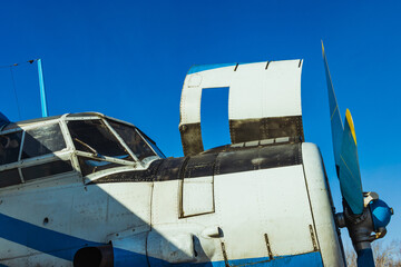 White sprinkles piston aircraft engine with an open hood and a propeller on blue sky background.