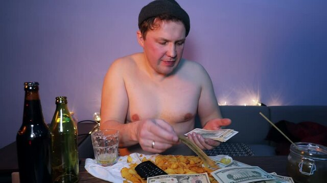Man counts money on the table with alcohol