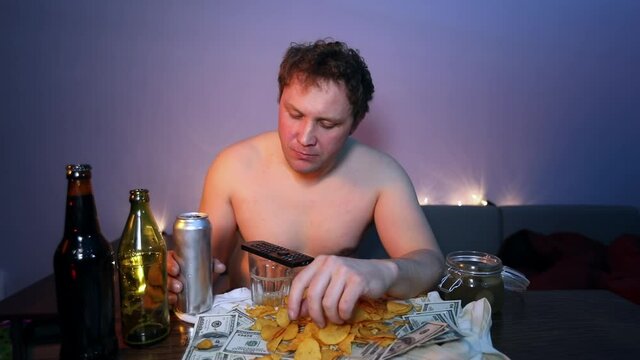 A drunkard watches TV, drinks beer and eats pickles cucumber