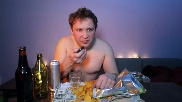 Redneck man watching TV laughs and eats chips