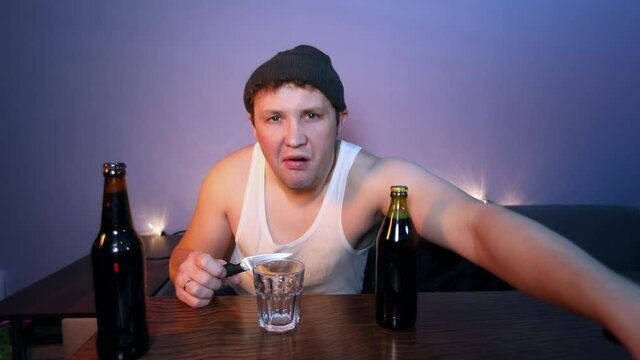 Peasant opens the beer, eats cucumbers and drinks alcohol