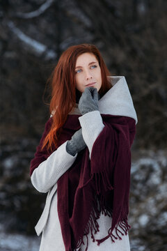 Sniling redheaded woman on winter walk. Outdoor portrait with beautiful ginger model in dark finter forest