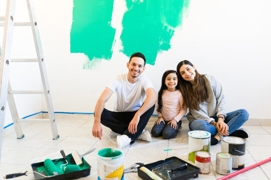 Portrait of a happy parents and daugther painting their house
