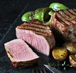 grill filet mignon and vegetables, grilled - young potatoes and peppers. steak mignon from the meat of young beef is shown in section, the degree of preparation is 