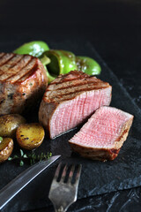 grill filet mignon and vegetables, grilled - young potatoes and peppers. steak mignon from the meat of young beef is shown in section, the degree of preparation is 