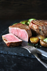 grill filet mignon and vegetables, grilled - young potatoes and peppers. steak mignon from the meat of young beef is shown in section, the degree of preparation is 