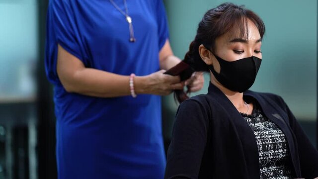 Young Asian woman at hairdresser salon wearing surgical protective face mask. New normal and social distancing concept