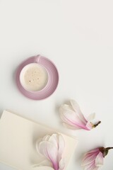 beautiful tender flat still life, card on a beige background, magnolia buds, a cup of cappuccino, concept of a floral spring background
