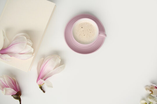 beautiful tender flat still life, card on a beige background, magnolia buds, a cup of cappuccino, concept of a floral spring background