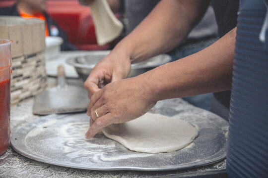 Selective focus shot of a male cook preparing pizza dough