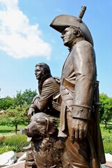 St. Charles, Missouri, USA: Lewis and Clark statue in Frontier Park near Missouri River. A bronze monument features Meriwether Lewis and William Clark and Clark's Newfoundland dog, Seaman. - obrazy, fototapety, plakaty