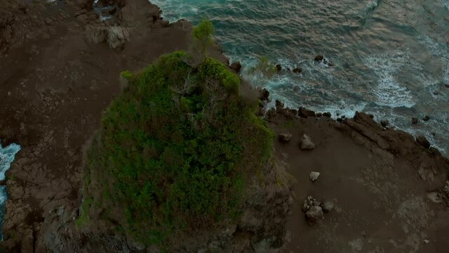 Volcanic rock beach aerial footage in Java Island, Indonesia. Taken from drone flying backward with parallax effect