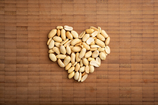 love concept image of heart shape made of peeled peanuts on bamboo cutting board background