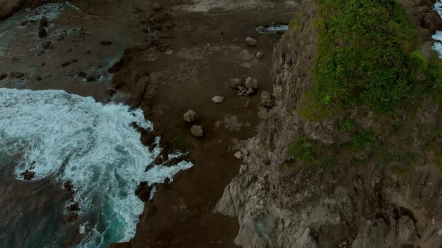 Volcanic rock beach cinematic aerial footage in Java Island, Indonesia. Taken from drone flying down forward slowly