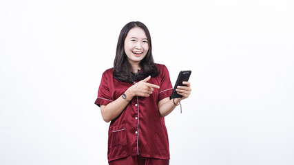 Portrait of young Asian woman wearing pajama pointing phone isolated white background