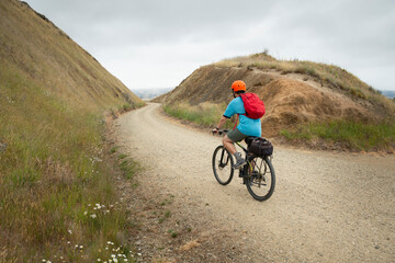 A young man cycling the Otago Central Rail Trail at Poolburn Gorge, South Island, New Zealand