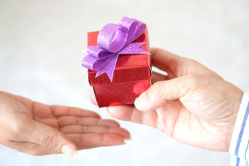 hand of woman holds a red gift box to hand woman. she is preparing to give her lover.