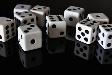 A close up image of several white dice on a black reflective table top. 