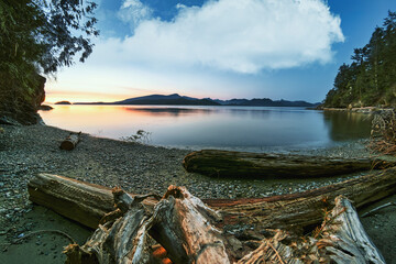 Fototapeta na wymiar The lush and vibrant natural temperate rain forest of the Pacific North West on Bowen Island. Crayola beach stretches out over Howe Sound with a stunning sunset.