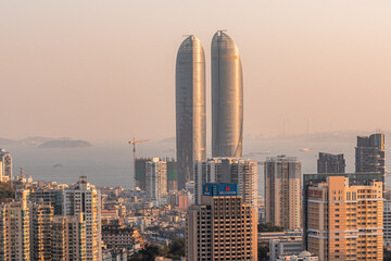Xiamen city skyline with modern buildings, twin towers, old town and sea at dusk
