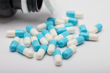 Many capsule pills and drug bottle on white background