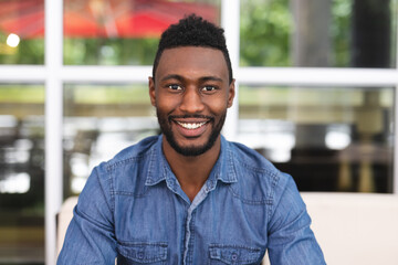 Portrait of african american man sitting in a cafe looking at camera and smiling