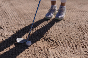 Low section of caucasian woman playing golf positioning club before taking shot from bunker