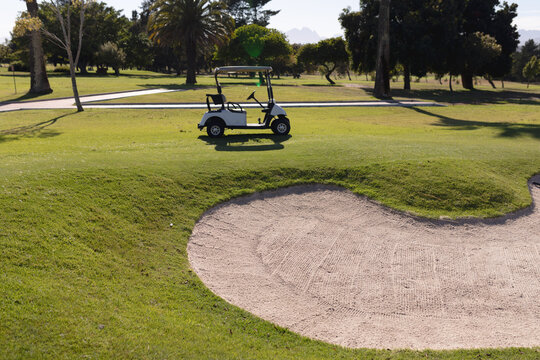 Golf cart parked on a golf course by a bunker