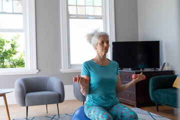 Senior caucasian woman wearing sports clothes exercising in living room